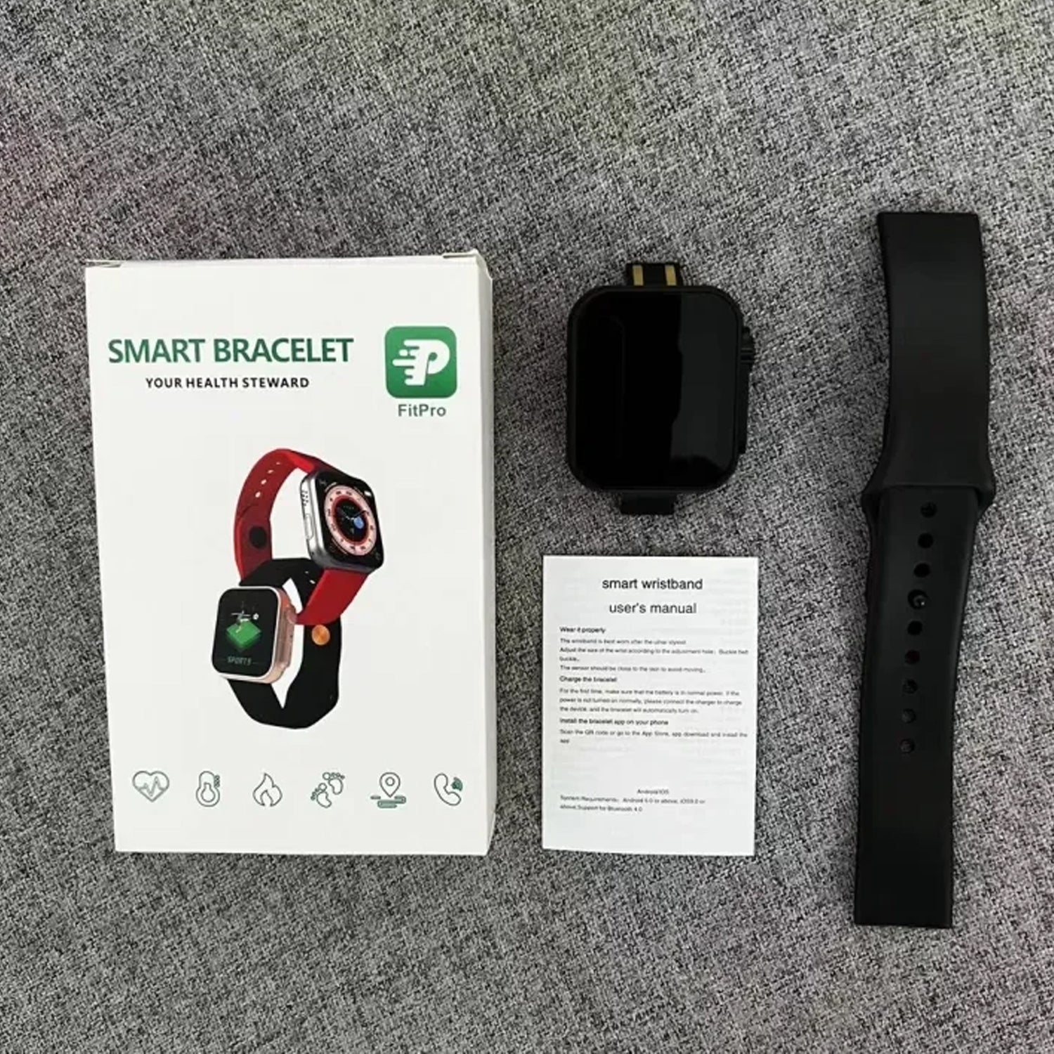 Smart bracelet packaging with device, charger, and user manual on a gray surface
