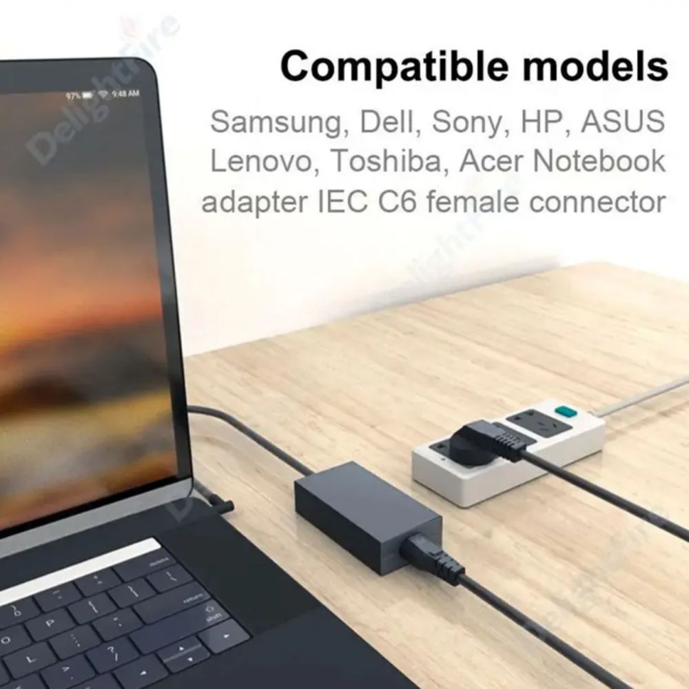 A laptop adapter cable setup on a light wood desk, with a laptop plugged in on the left and a power strip on the right. Text at the top reads 'Compatible models' listing Samsung, Dell, Sony, HP, ASUS, Lenovo, Toshiba, and Acer Notebook adapter IEC C6 female connector.